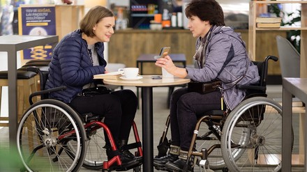 Zwei Frauen mit Rollstuhl in einem Café