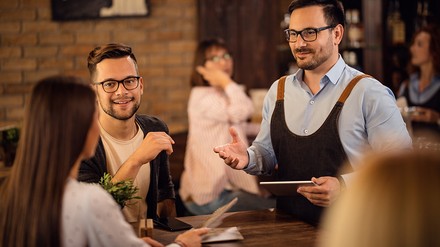 Kellner möchte Bestellung aufnehmen.