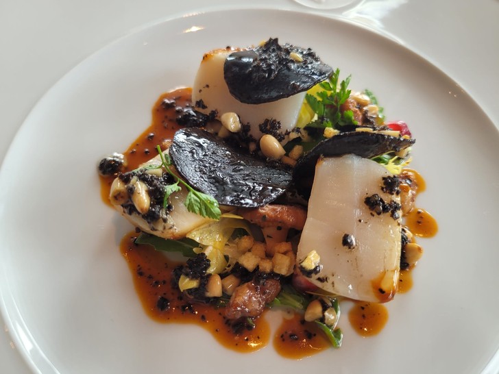 Salat von gebratener Sankt-Jakobsmuschel mit Rucola und Löwenzahn, geschwenkten Pfifferlingen und schwarzem Trüffel