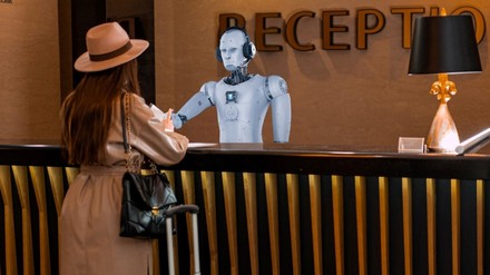 Frau steht an der Rezeption vor einem Roboter