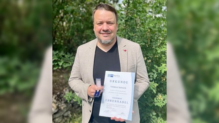 Porträt von Thomas Rieger mit Urkunde und Ehrennadel