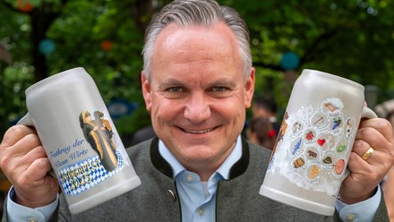 Wirtschaftsreferent Christian Scharpf (SPD) hält den offiziellen Bierkrug der Wiesn-Wirte für das Jahr 2025 in der Hand.