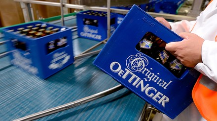 Eine Kiste Oettinger-Bier wird in der Oettinger Brauerei in Braunschweig auf ein Transportband gestellt