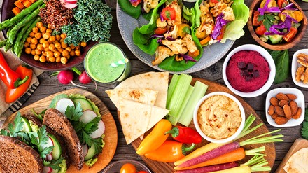 Gesunder Essens-Tisch mit Buddha-Bowl, Salat, Wraps, Gemüse und Sandwiches. Draufsicht über einem Holz-Hintergrund.