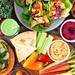 Gesunder Essens-Tisch mit Buddha-Bowl, Salat, Wraps, Gemüse und Sandwiches. Draufsicht über einem Holz-Hintergrund.
