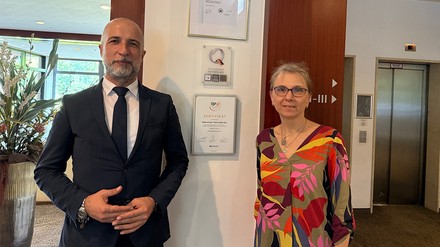 Ergün Ersoy (Residence Manager) und Annette Heim (Verwaltung) vor dem ServiceQ-Siegel
