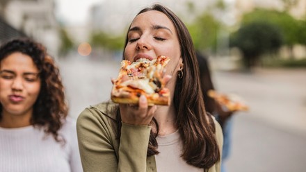 Junge Frau beißt in eine Pizza.