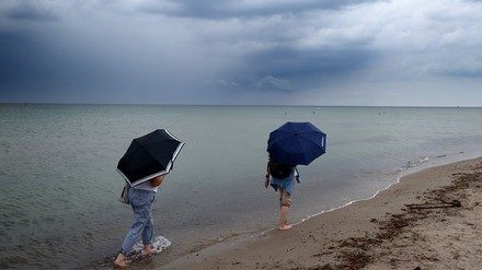 Zwei Menschen laufen mit Regenschirm über den Strand