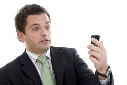 Geschäftsmann sieht erstaunt auf sein Handy