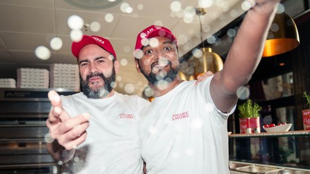 Zwei Mitarbeiter von L’Osteria lachen in die Kamera