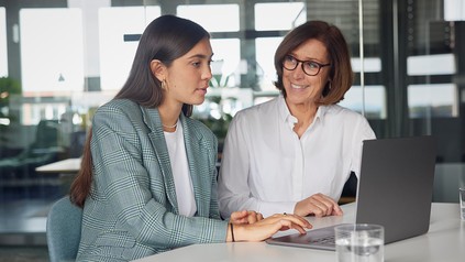 eine junge und eine ältere Frau schauen gemeinsam in einen Laptop