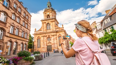 Ein Mädchen auf Reisen, das ein Foto der Johanniskirche (St. John Baptist Church) in Saarbrücken macht.