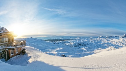 Verschneite Berglandschaft mit einer kleinen Berghütte im Sonnenschein