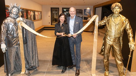 Birgit Maier und Alexander Strobl schneiden beim Opening der „World of Congress“ im Hotel Gut Brandlhof ein Band durch; daneben stehen zwei Künstler als goldene Statuen.