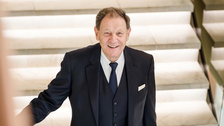 Hotelmanager in dunklem Anzug auf einer beleuchteten Treppe in einem modernen Gebäude