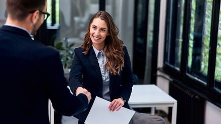 Lächelnde Bewerberin und Geschäftsmann beim Vorstellungsgespräch, Handschlag im Interview