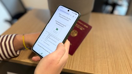 Person scannt Reisepass mit dem Smartphone für den digitalen Self-Check-in in einer Unterkunft.