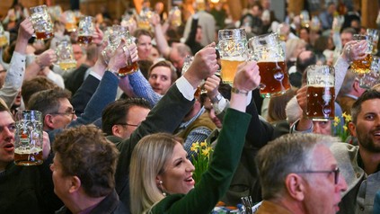 Gäste erheben beim Starkbieranstich der Giesinger Brauerei auf dem Firmengelände die Bierkrüge.