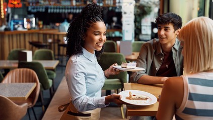 Kellnerin bringt Kuchen an den Tisch