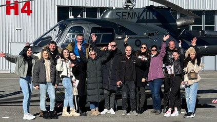 Team des Upside Down Town Hotel Neue Post vor dem Helikopter