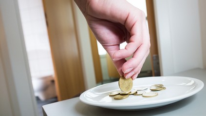 Person bezahlt Toilettengebühr vor Restauranttoilette.