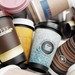 Haufen aus gebrauchten Einweg-Kaffeebechern mit Deckeln als Symbol für Verpackungsmüll im To-go-Bereich