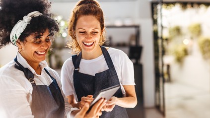 Restaurantmitarbeiterinnen nutzen ein Tablet zur digitalen Steuerung von Abläufen im Gastronomiebetrieb