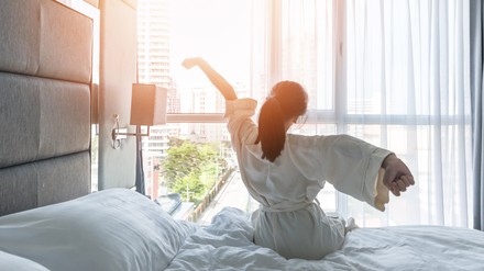 Die Zahl der Übernachtungen in Hotels, Pensionen, Ferienhäusern und Co. lag trotz einer leichten Erholung im vergangenen Jahr um 37,4 Prozent unter dem Niveau des Vorkrisenjahres 2019. (Foto: © Chinnapong/stock.adobe.com)
Hotel room comfort with good sleep easy relaxation lifestyle of Asian girl on bed have a nice day morning waking up, taking some rest, lazily relaxing in guest bedroom in city hotel