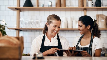 Mitarbeiter in einem Café besprechen gemeinsam Inhalte auf einem Tablet