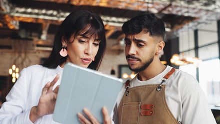 Restaurantteam bespricht am Tablet die Dienstplanung im Betrieb