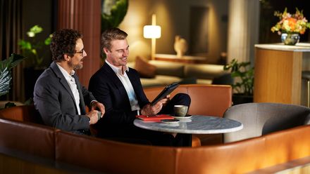 Zwei Männer sitzen mit Tablett in Hotellobby