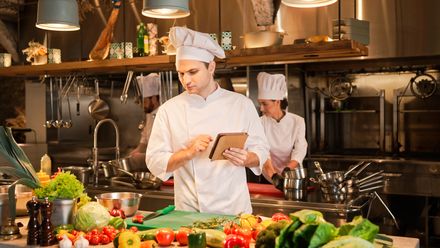 Koch bereitet in einer Restaurantküche frische Zutaten für ein Gericht zu.