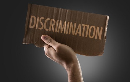 Mann hält Pappe mit Inschrift „Discrimination“