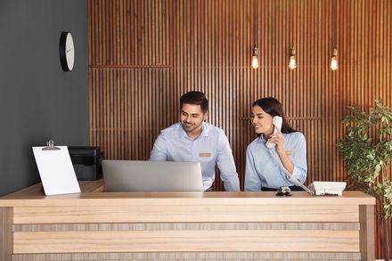 Zwei Mitarbeiter arbeiten an der Rezeption einer modernen Hotellobby.