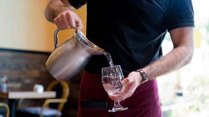 Kellner schenkt Wasser in ein Glas ein