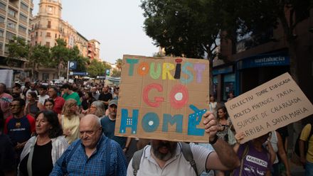 Ein Teilnehmer des Protestzugs in Palma hält ein Schild mit der Aufschrift „Tourists go home“ während einer Demonstration gegen den Tourismus auf Mallorca.