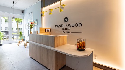Rezeption des Candlewood Suites Berlin Airport mit Empfangstresen und Markenlogo an der Wand.