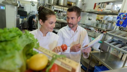 Zwei Köche prüfen frische Lebensmittel in einer Restaurantküche.