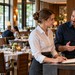 Drei Kollegen aus Service, Restaurantleitung und Küche besprechen gemeinsam Reservierungen in einem Hotelrestaurant.