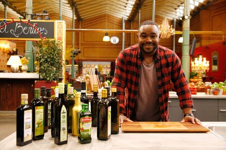 Nelson Müller vor einem Holzbrett neben dem diverse Öle stehen