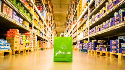 Eine grüne Papiertüte auf der getnow.de steht in einem Supermarkt