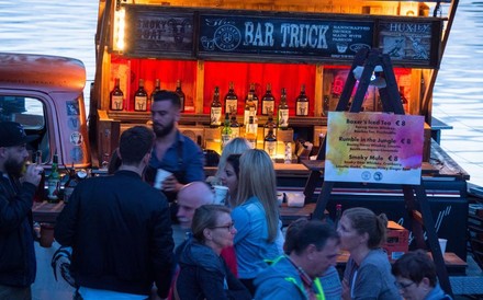 Mehrere Menschen tummeln sich vor einem Stand namens Bar Truck