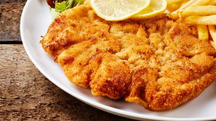 Ein Teller mit Schnitzel, Zitronenscheiben, Pommes und Salat