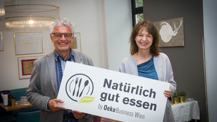 Thomas Hruschka und Karin Büchl-Krammerstätter halten ein Schild hoch auf dem Natürlich gut essen by Oeko Business Wien steht