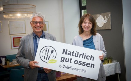 Thomas Hruschka und Karin Büchl-Krammerstätter halten ein Schild hoch auf dem Natürlich gut essen by Oeko Business Wien steht