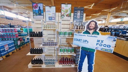 Ein Regal in einem Metromarkt mit einem Aufsteller auf dem Start Ups NX Food steht