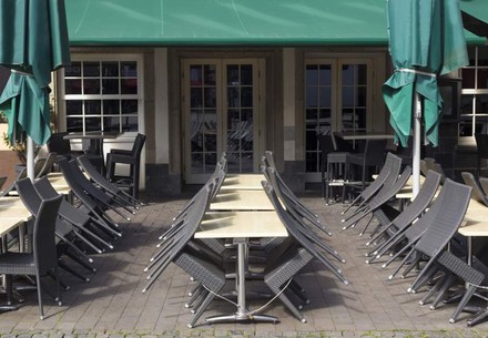 Ein geschlossener Außenbereich eines Restaurants mit an die Tische gelehnten Stühlen