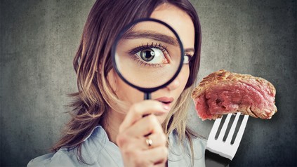 Eine Frau inspiziert ganz genau ein Stück Fleisch