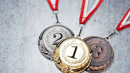 Eine goldene, eine silberne und eine bronzene Medaille an roten Bändern