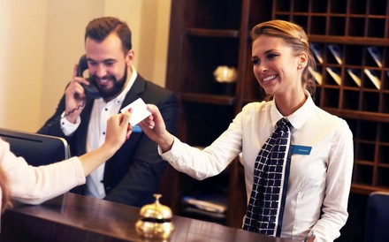 Zwei freundliche Mitarbeiter bedienen einen Kunden an der Hotelrezeption